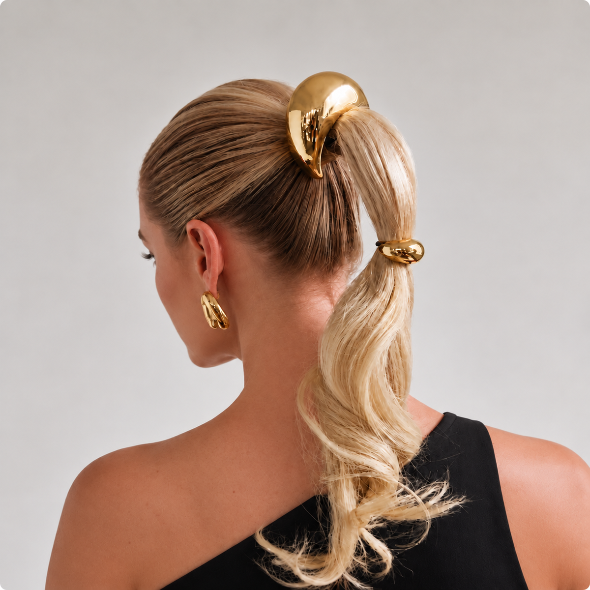 Nest Pony Cuff gold shown in blonde ponytail with a black one-shoulder top